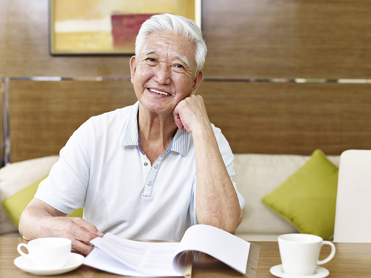 Elderly man sitting at a table.